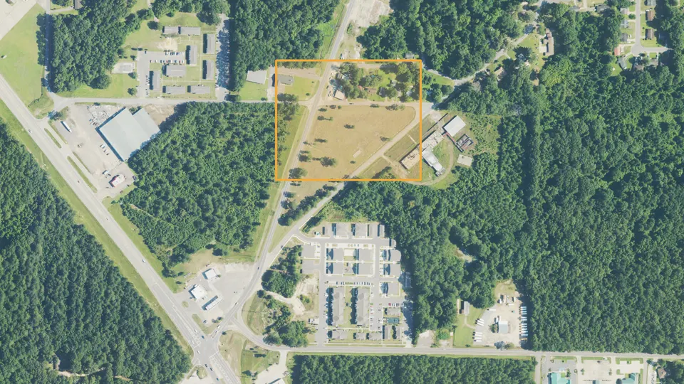The same area in July 2023. An apartment complex now stands where the drive-in was, and the outlined register location is still an empty field and woods.