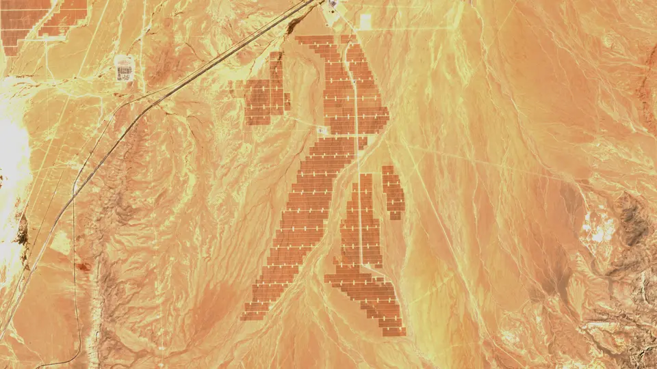 The same frame in May 2024, with the dark rectangular blocks of the completed solar plant covering the center of the image.